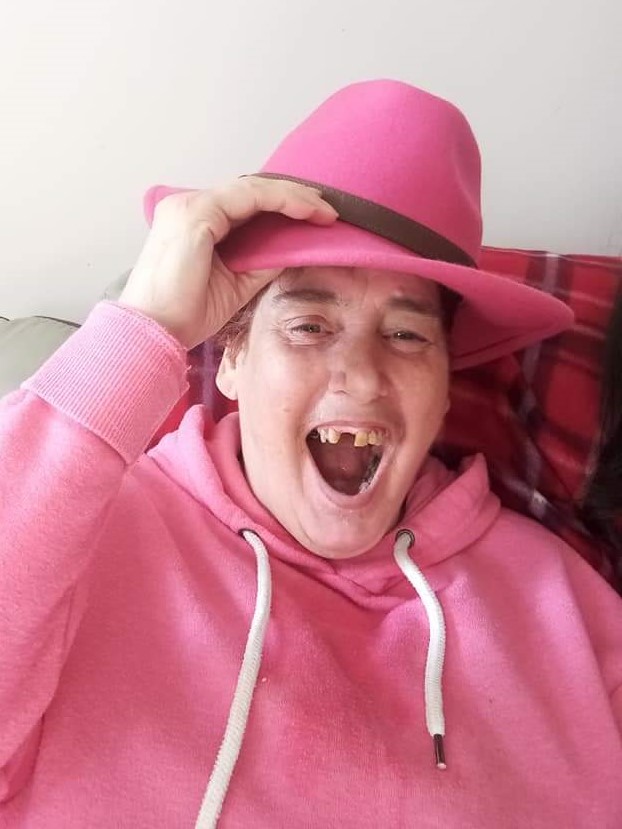 Libby, a resident of the L'Arche community in Inverness, Scotland, smiles with a pink hat and sweatshirt