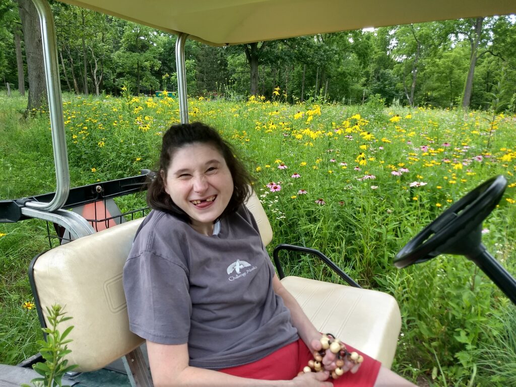 Emily Graber sitting in a golf cart in a wildflower meadow
