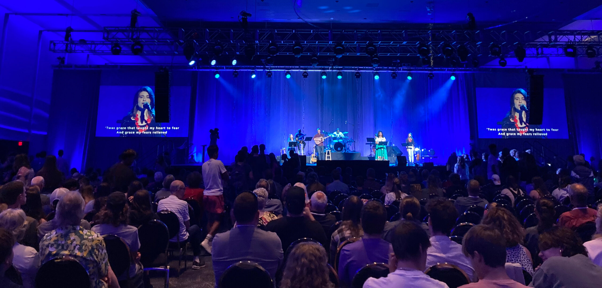 Lots of people in a large worship space with blue lighting