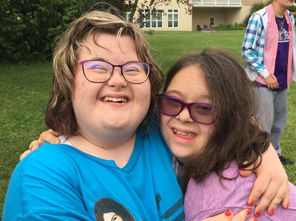 photo of two young adults with intellectual disabilities hugging and smiling excitedly at the camera