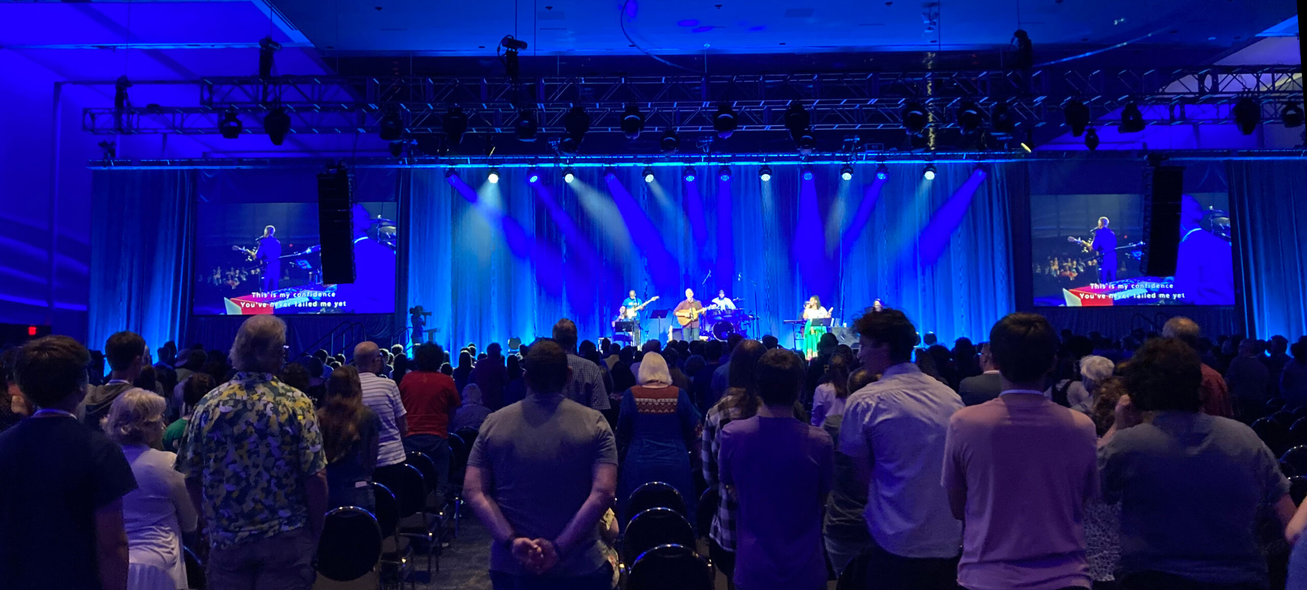 a stage lit with blue light, a crowd of people in the foreground