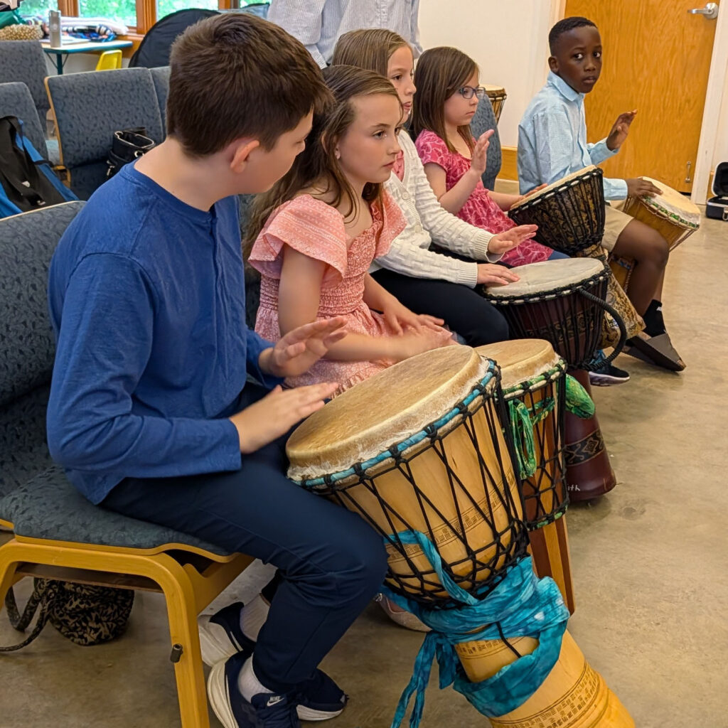 children playing with large African drums