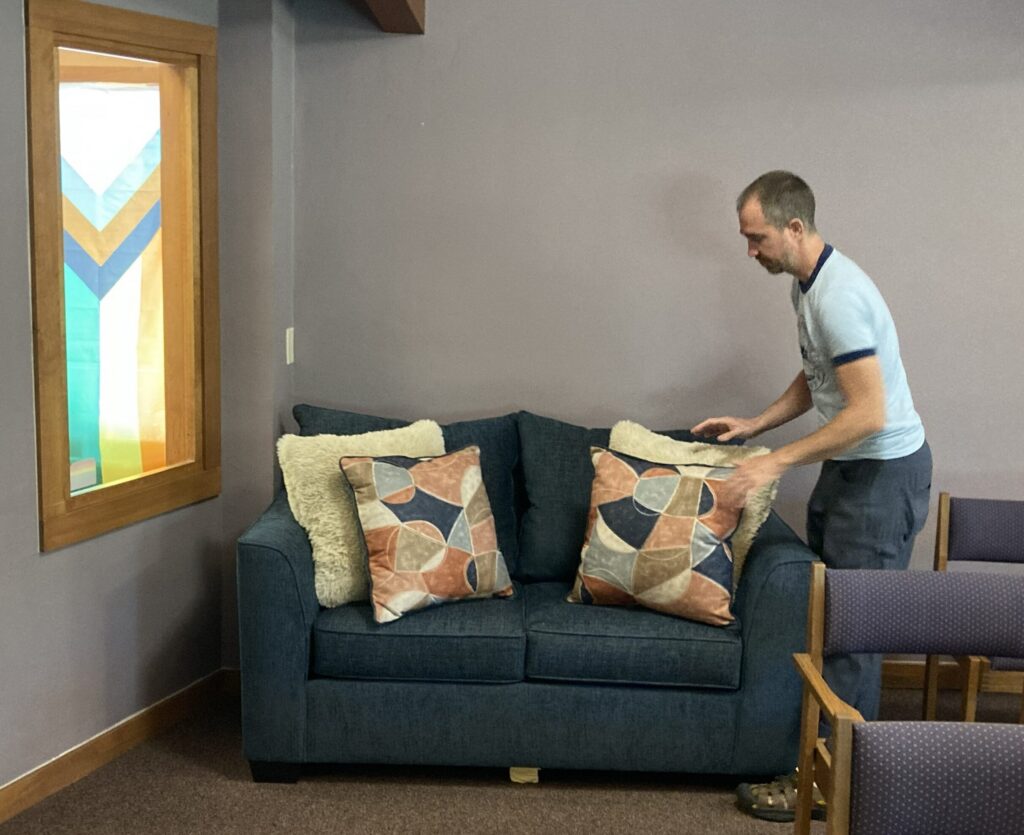 a man putting pillow on a blue two-seated couch